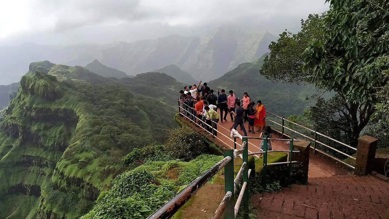 Tourists enjoying the misty Sahyadri valley view from Arthur's Seat, Mahabaleshwar
