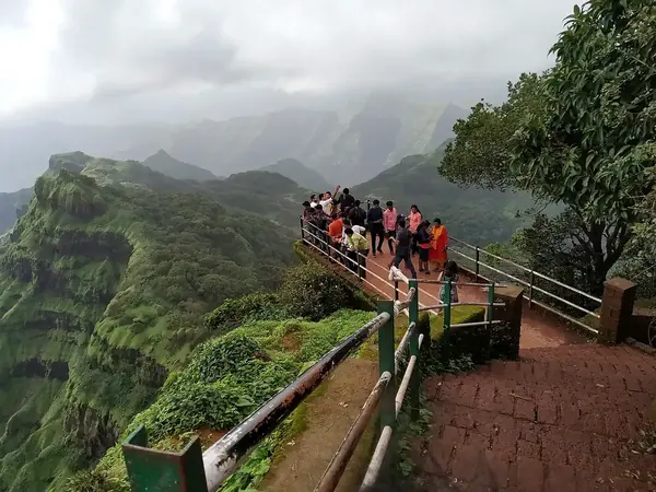Tourists at Arthur's Seat viewpoint in Mahabaleshwar overlooking misty green Sahyadri valleys